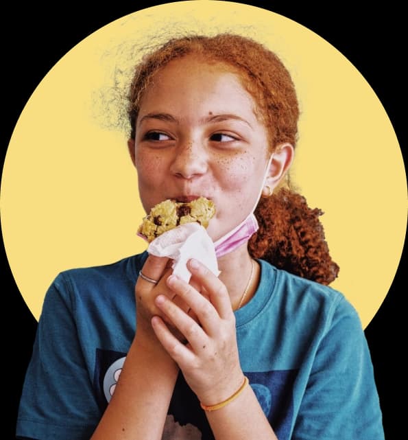 Girls smiling eating a chocolate chip cookie